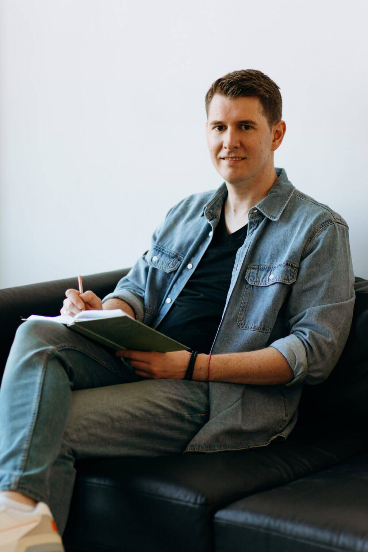 Matthias Eichhorn – Hypnose & Coaching in Bensheim an der Bergstraße Matthias Eichhorn, Hypnose Coach in Bensheim, sitzt entspannt auf einem Sessel und macht sich Notizen während einer Coaching-Sitzung